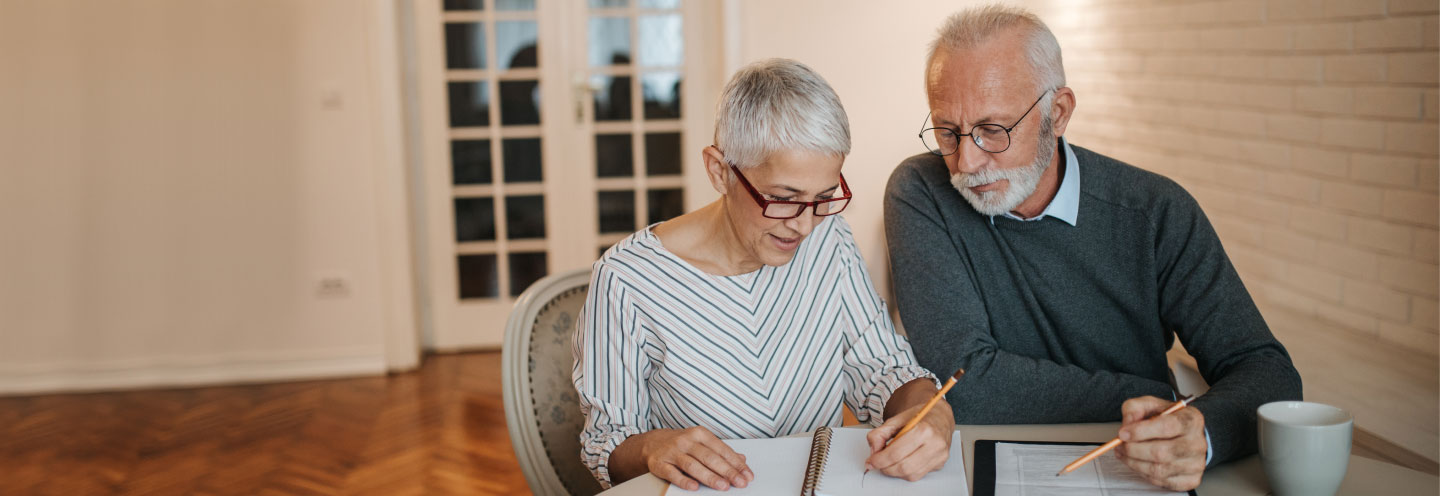 Coppia seduta a tavola intenta a fare i conti su alcuni fogli