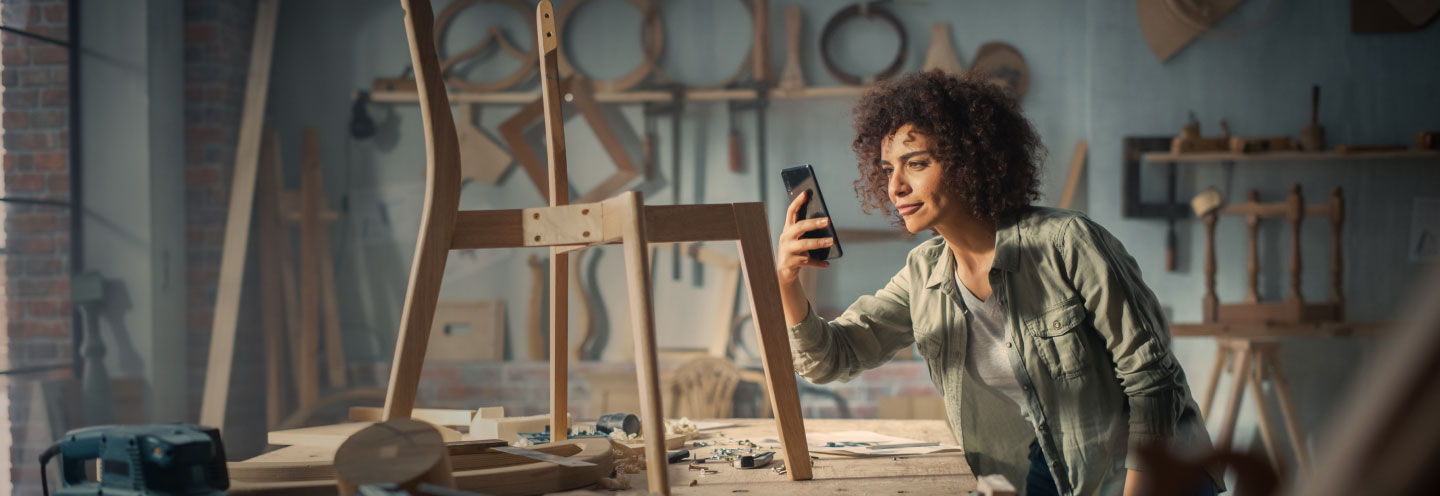 Ragazza che fotografa una sedia in legno in lavorazione in una falegnameria